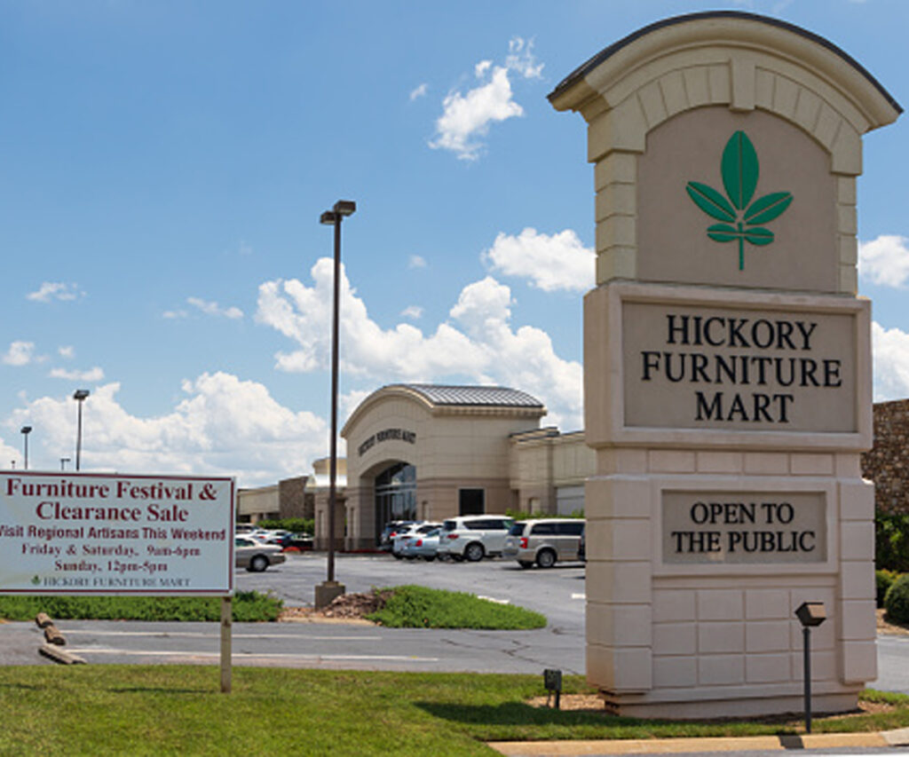 Why Visit Amish Oak & Cherry at the Hickory Furniture Mart 5 Hickory Furniture Mart entrance sign with showroom building and parking lot behind.